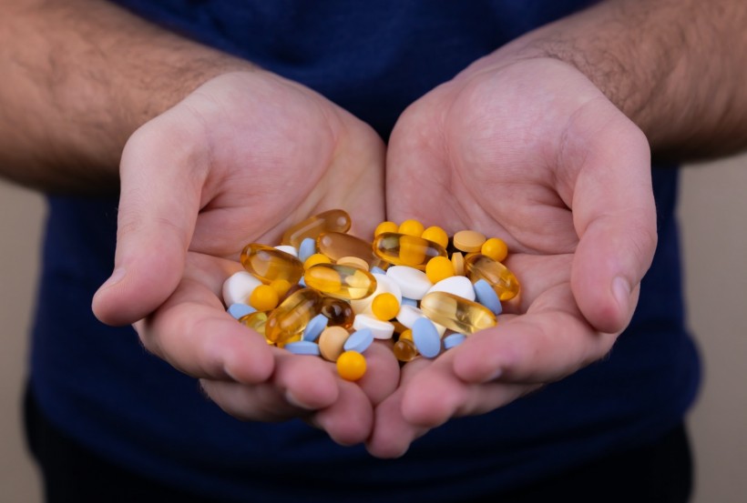 A pile of multi-colored pills in a male hand