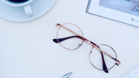 Brown Framed Eyeglasses Near Cup of Coffee on White Surface