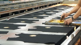 a person cutting fabric on a conveyor belt