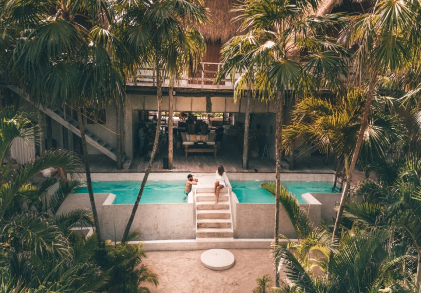 man and woman swimming at pool surrounded by trees (Tulum, Mexico)