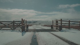 a snow covered road with a wooden gate