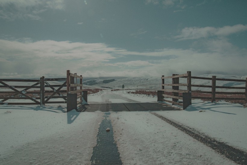 a snow covered road with a wooden gate