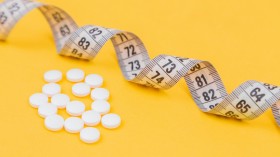 White measuring tape with white pills, white vitamin on a yellow background.