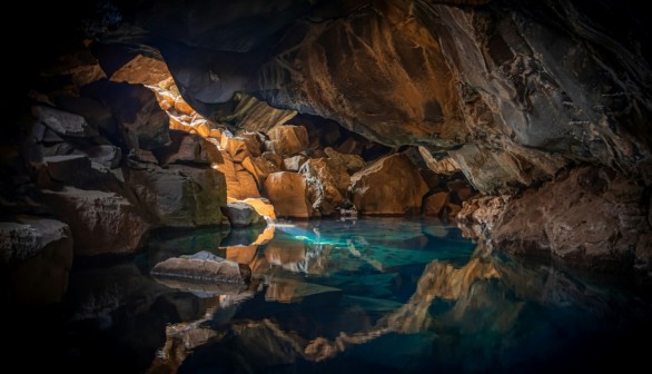  cave surrounded with blue body of water