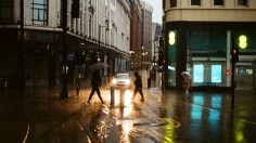  a group of people walking across a street holding umbrellas