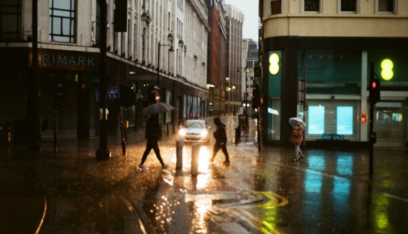  a group of people walking across a street holding umbrellas