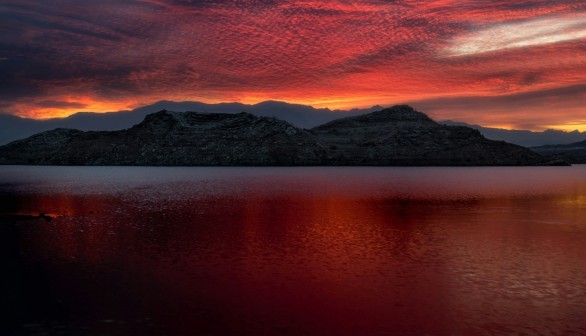 a beautiful sunset over a lake with mountains in the background