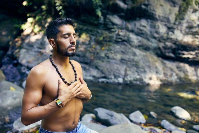 Man meditating near water