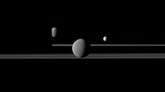 The Cassini spacecraft observes three of Saturn's moons set against the darkened night side of the planet.