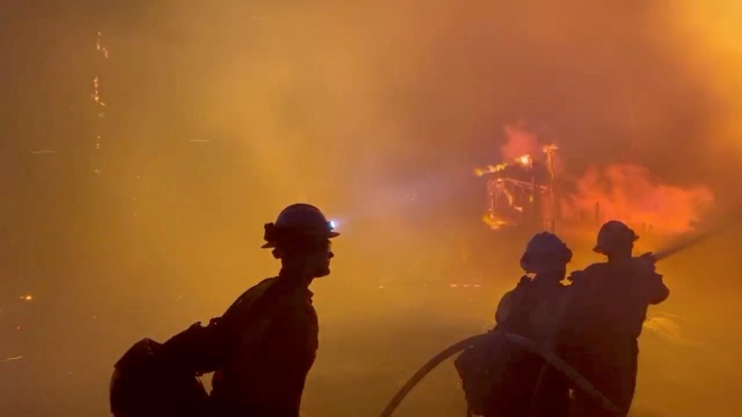 Firefighters direct water on a burning house during wildfires in San Bernardino, California